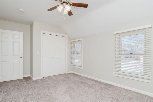 unfurnished bedroom featuring a closet, lofted ceiling, light colored carpet, and ceiling fan