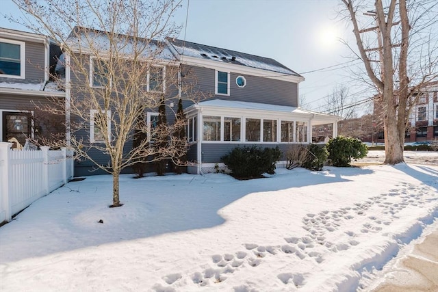 snow covered house featuring a sunroom