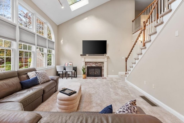 3 Anders Way, Acton, MA 01720 - carpeted living area featuring high vaulted ceiling, baseboards, a skylight, stairs, and a glass covered fireplace