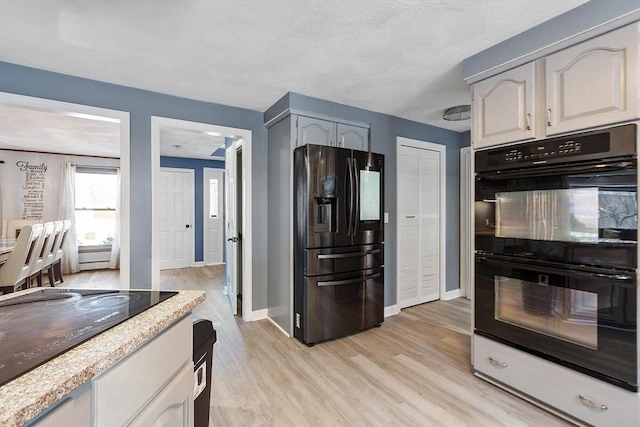 kitchen with light hardwood / wood-style floors, white cabinets, and black appliances