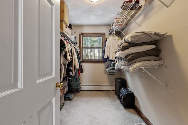 spacious closet featuring light colored carpet and a baseboard heating unit