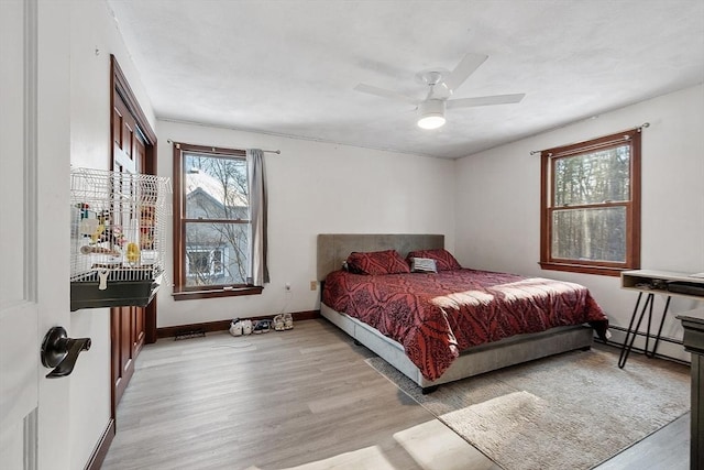 bedroom with ceiling fan, baseboard heating, and light hardwood / wood-style flooring