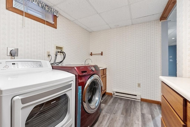 clothes washing area featuring cabinets, washer and dryer, hardwood / wood-style floors, and a baseboard radiator