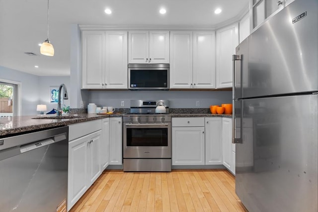 31-33 New Ocean St, Swampscott, MA 01907 - kitchen featuring stainless steel appliances, white cabinetry, light wood-style floors, decorative light fixtures, and dark stone countertops