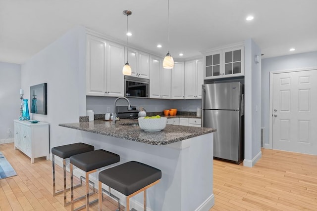 31-33 New Ocean St, Swampscott, MA 01907 - kitchen with freestanding refrigerator, light wood-style flooring, white cabinetry, a breakfast bar, and recessed lighting