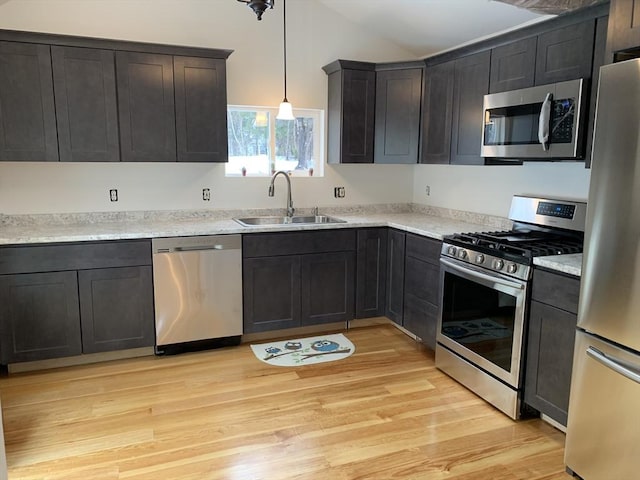 kitchen featuring pendant lighting, sink, stainless steel appliances, and light hardwood / wood-style floors