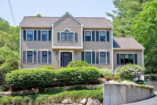 colonial home featuring a shingled roof