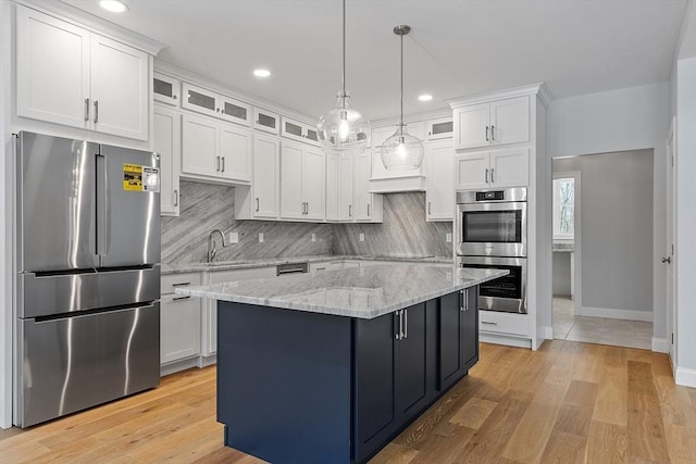 kitchen featuring appliances with stainless steel finishes, pendant lighting, white cabinetry, decorative backsplash, and a center island