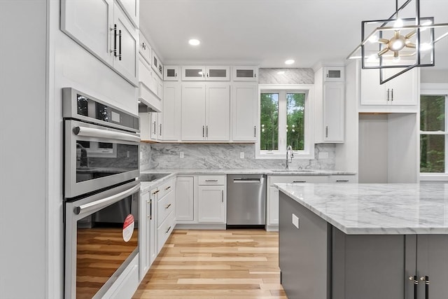 kitchen featuring sink, light wood-type flooring, appliances with stainless steel finishes, light stone countertops, and white cabinets