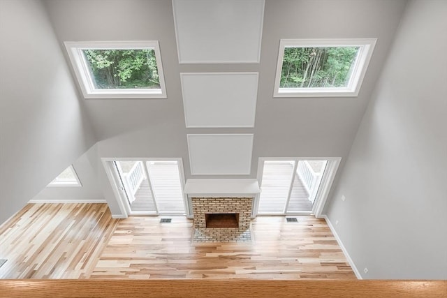 unfurnished living room with plenty of natural light, a brick fireplace, and a high ceiling