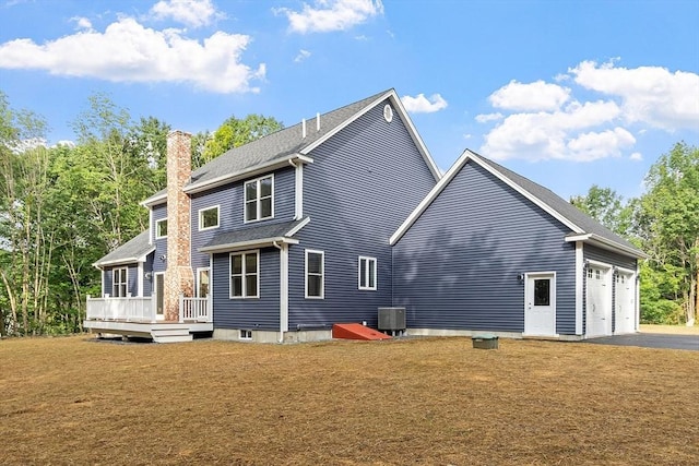 rear view of house featuring a wooden deck, a garage, a lawn, and central air condition unit