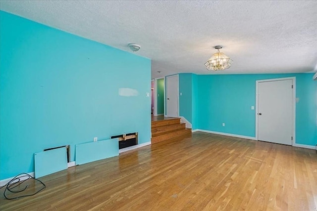 7 Wilbur Ct, Saugus, MA 01906 - unfurnished room featuring a textured ceiling, a chandelier, wood finished floors, stairway, and baseboards