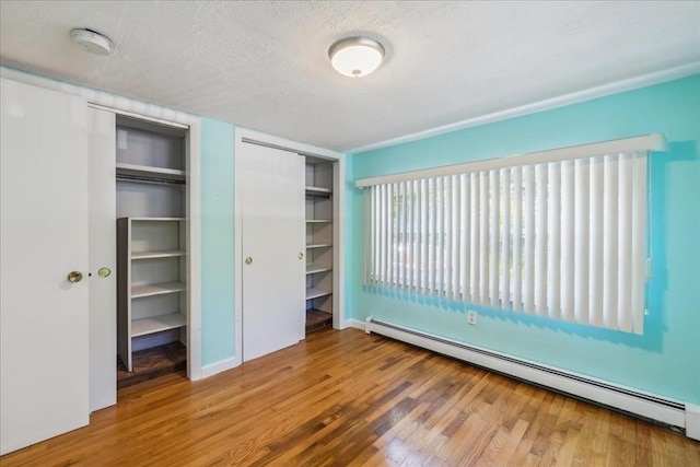 7 Wilbur Ct, Saugus, MA 01906 - unfurnished bedroom with baseboard heating, wood finished floors, a textured ceiling, and multiple closets