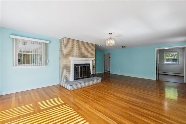 7 Wilbur Ct, Saugus, MA 01906 - unfurnished living room with a baseboard heating unit, wood finished floors, a chandelier, a fireplace, and a baseboard radiator