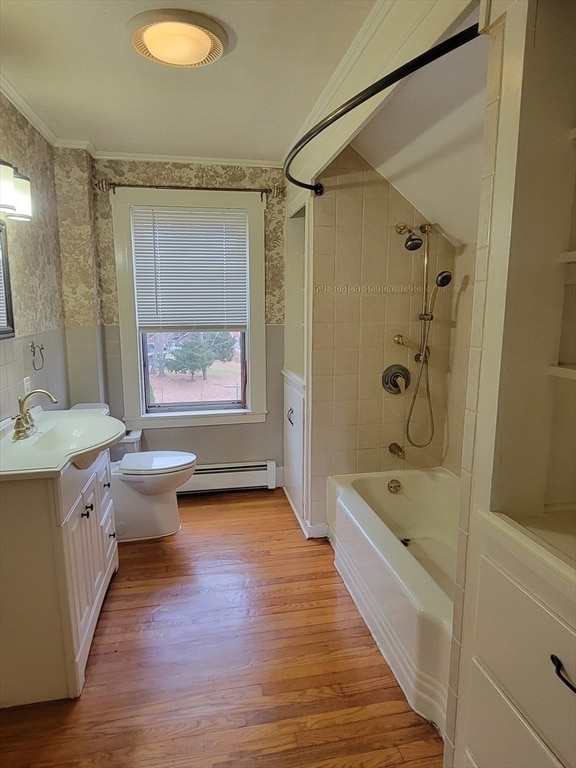 full bathroom featuring wood-type flooring, toilet, tiled shower / bath combo, baseboard heating, and vanity