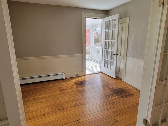 unfurnished room featuring light wood-type flooring and a baseboard heating unit