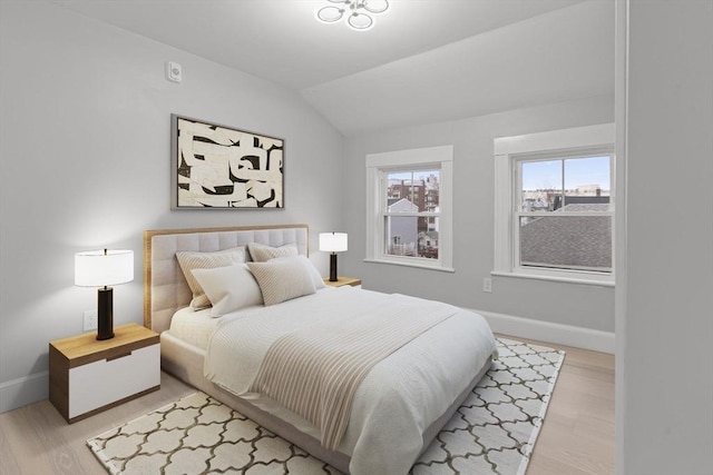 bedroom with baseboards, light wood-style floors, and vaulted ceiling