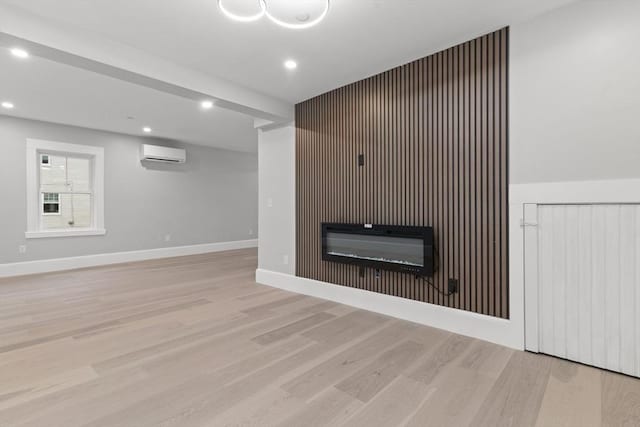 unfurnished living room featuring light wood-type flooring, recessed lighting, a glass covered fireplace, and a wall mounted AC