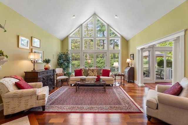 living area featuring ornate columns, high vaulted ceiling, and wood finished floors
