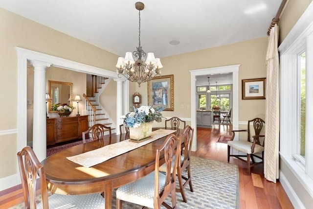 dining room featuring wood finished floors, a chandelier, stairs, and baseboards