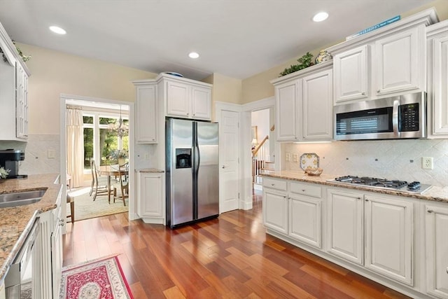 kitchen featuring appliances with stainless steel finishes, white cabinets, dark wood-type flooring, backsplash, and recessed lighting