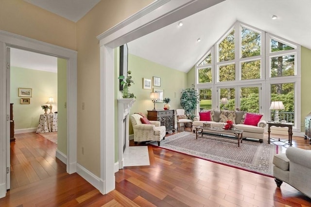 living room featuring high vaulted ceiling, hardwood / wood-style floors, and baseboards