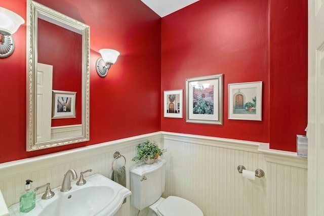 half bath featuring wainscoting, a sink, and toilet