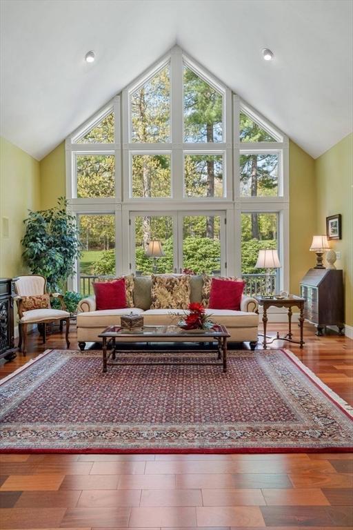 living area with high vaulted ceiling, plenty of natural light, and wood finished floors