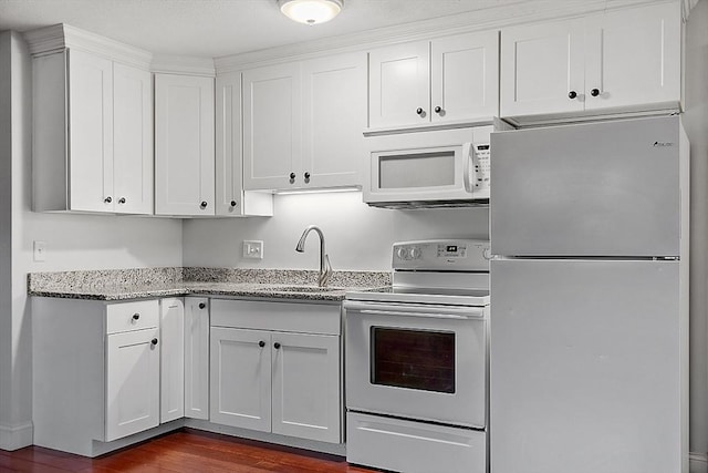 kitchen with light stone counters, white appliances, sink, dark hardwood / wood-style floors, and white cabinetry