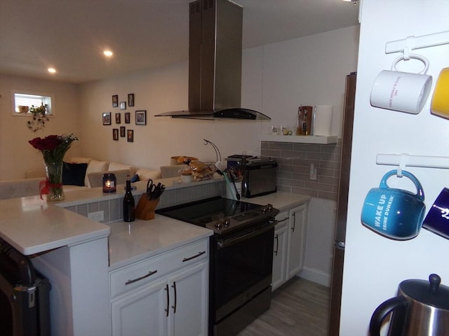 kitchen with white cabinets, white fridge, stainless steel range with electric stovetop, and range hood