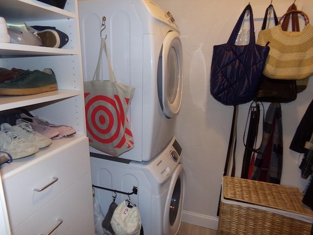 clothes washing area with hardwood / wood-style flooring and stacked washer / drying machine