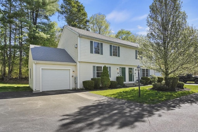 colonial inspired home featuring a front lawn, a shingled roof, a garage, and aphalt driveway
