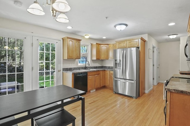 kitchen with dishwasher, a sink, stainless steel fridge, dark countertops, and range with electric stovetop