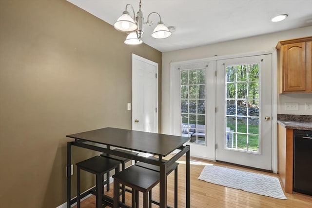 dining area with baseboards, a notable chandelier, and light wood-style flooring