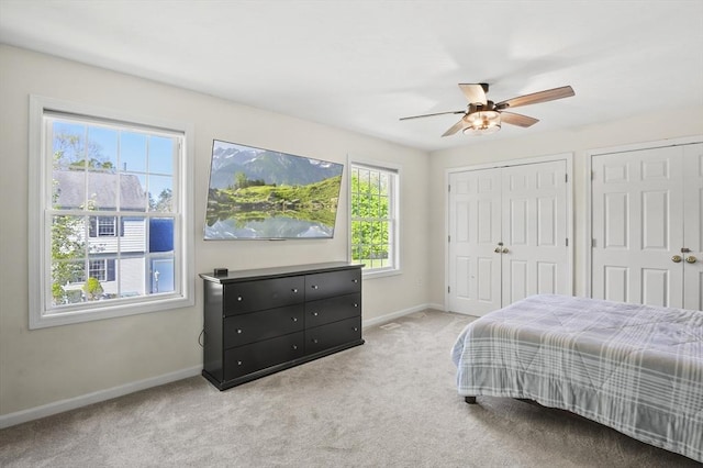 carpeted bedroom featuring baseboards, multiple closets, and ceiling fan