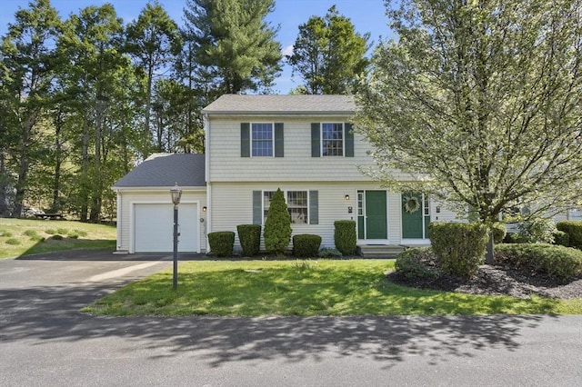 colonial-style house featuring a front yard, entry steps, a garage, and aphalt driveway