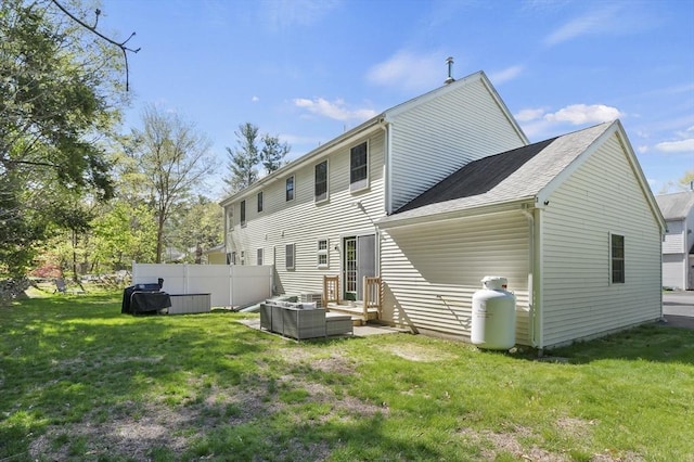 rear view of house featuring outdoor lounge area, fence, and a lawn