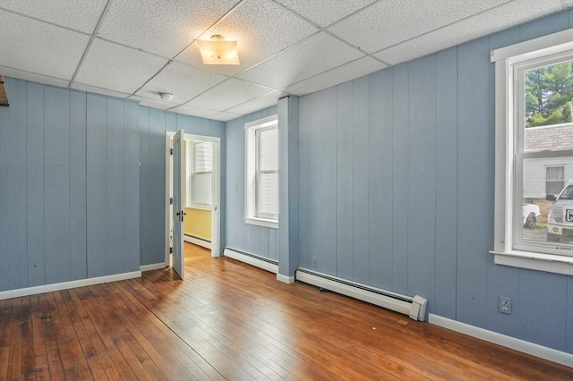 270 Main St, Oxford, MA 01540 - empty room featuring wood-type flooring, a drop ceiling, baseboards, wood walls, and a baseboard heating unit