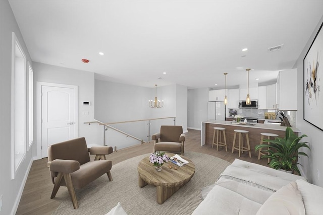 living area with light wood-style flooring, recessed lighting, visible vents, baseboards, and an inviting chandelier