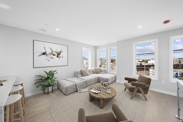 living area with recessed lighting, light wood-type flooring, visible vents, and baseboards