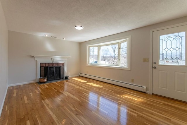 unfurnished living room with a baseboard heating unit, baseboards, a fireplace, hardwood / wood-style flooring, and a textured ceiling