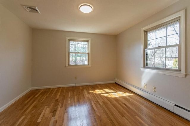 unfurnished room with baseboard heating, baseboards, light wood-style floors, and visible vents