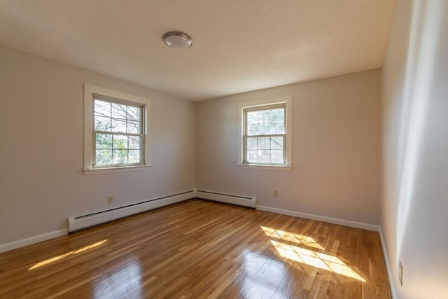 unfurnished room featuring a baseboard heating unit, baseboards, and wood finished floors