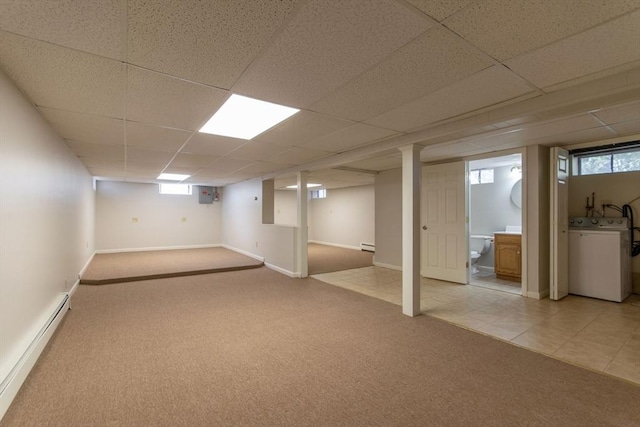 below grade area featuring light carpet, washer / dryer, a baseboard heating unit, and a paneled ceiling