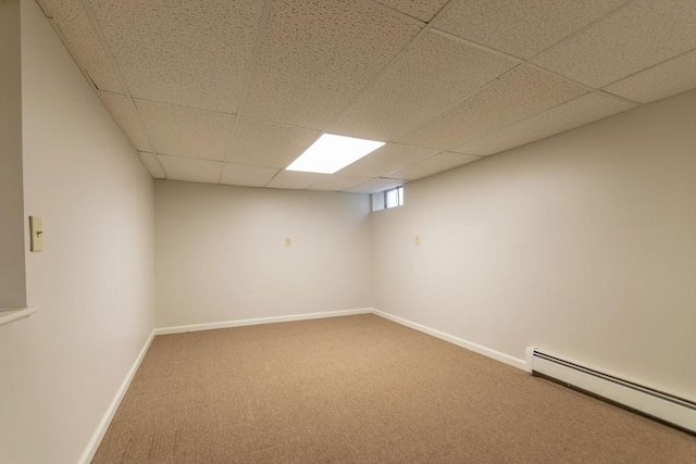 basement featuring a drop ceiling, a baseboard heating unit, baseboards, and carpet flooring