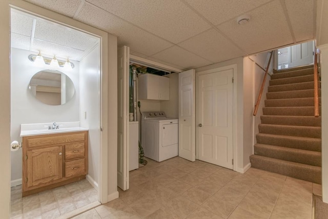 bathroom with washer and dryer, vanity, baseboards, and a drop ceiling