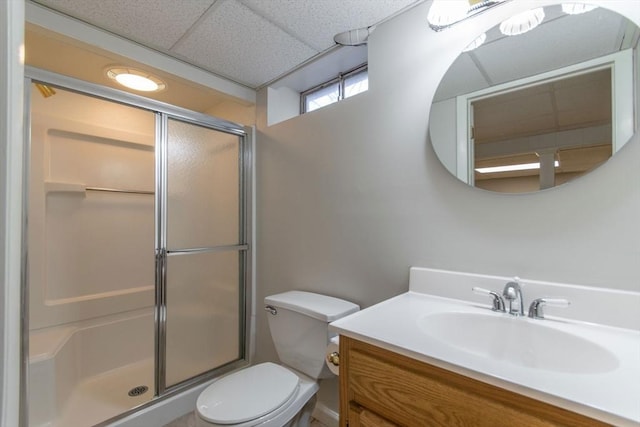 full bathroom featuring a drop ceiling, a stall shower, toilet, and vanity