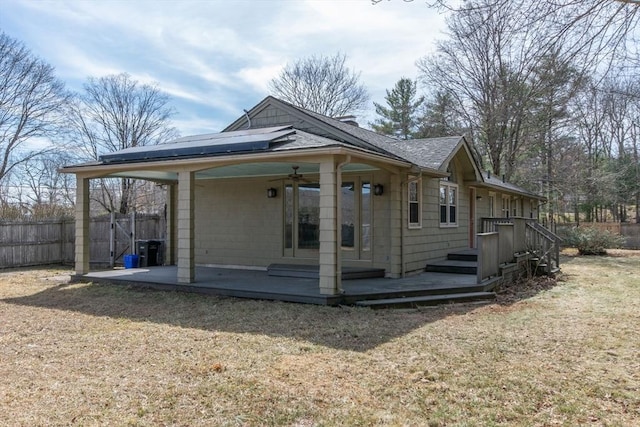 rear view of property with a ceiling fan, a patio, fence, a shingled roof, and solar panels