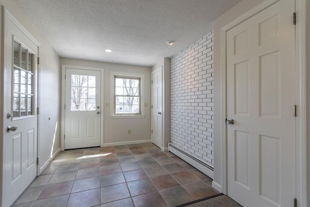 entryway featuring a baseboard heating unit, baseboards, a textured ceiling, and brick wall