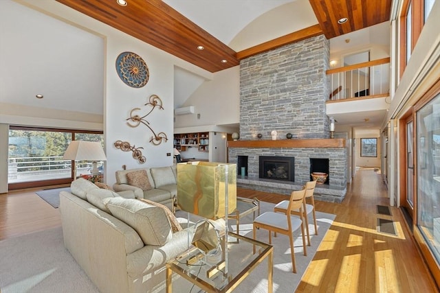 living room with a fireplace, recessed lighting, visible vents, light wood-style floors, and high vaulted ceiling